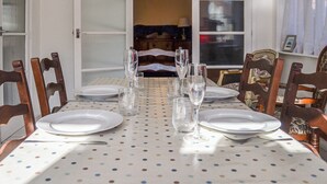 Une table à manger dressée pour six personnes, recouverte d’une nappe à pois, et entourée de chaises en bois.