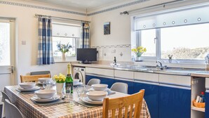 Cocina compacta con comedor, lavadora y ventana con cortinas.