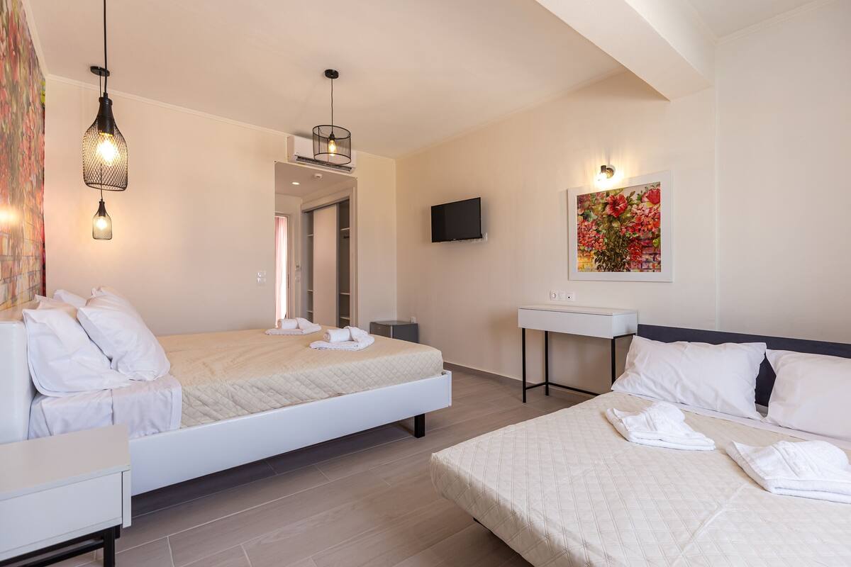 Quarto de hotel com cama, mesa de cabeceira e televisão fixada na parede.