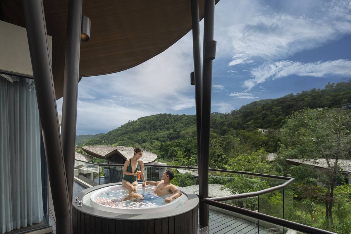 A hot tub on a balcony with a view of a forested hillside.