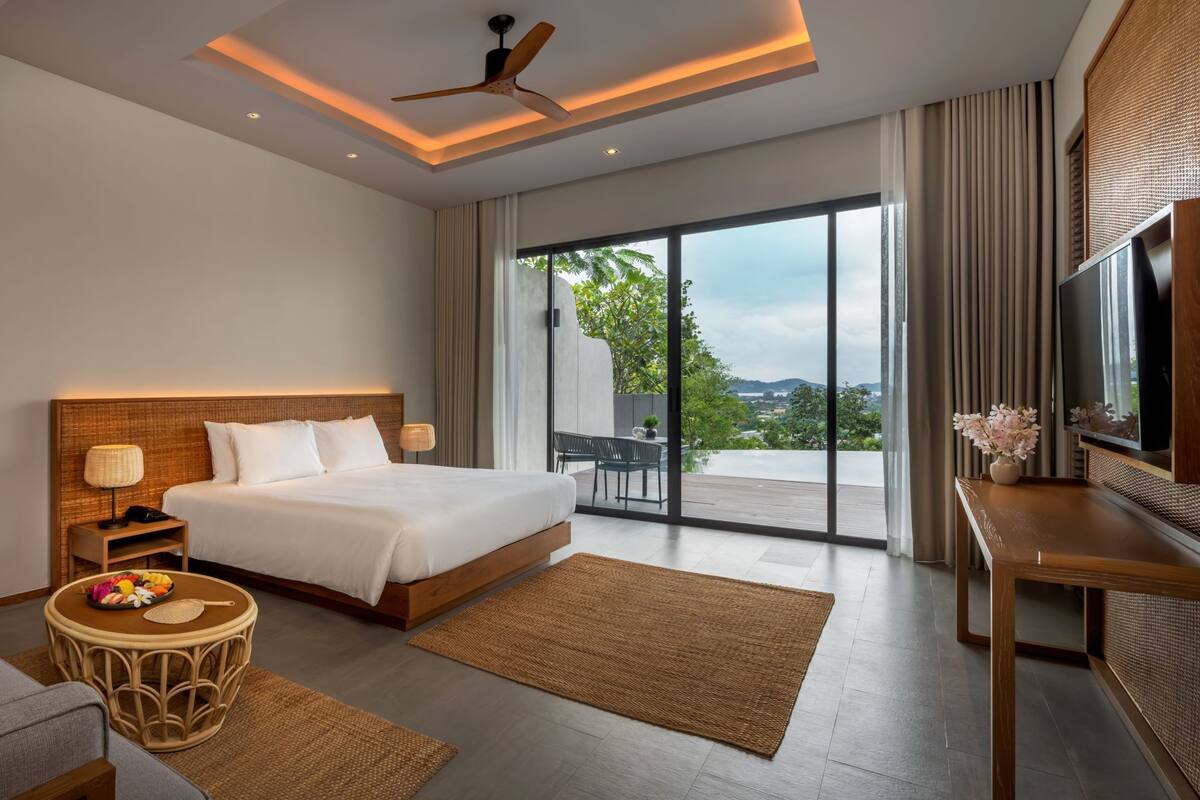 A modern hotel room with a large bed, a sofa, a round coffee table, and a TV.