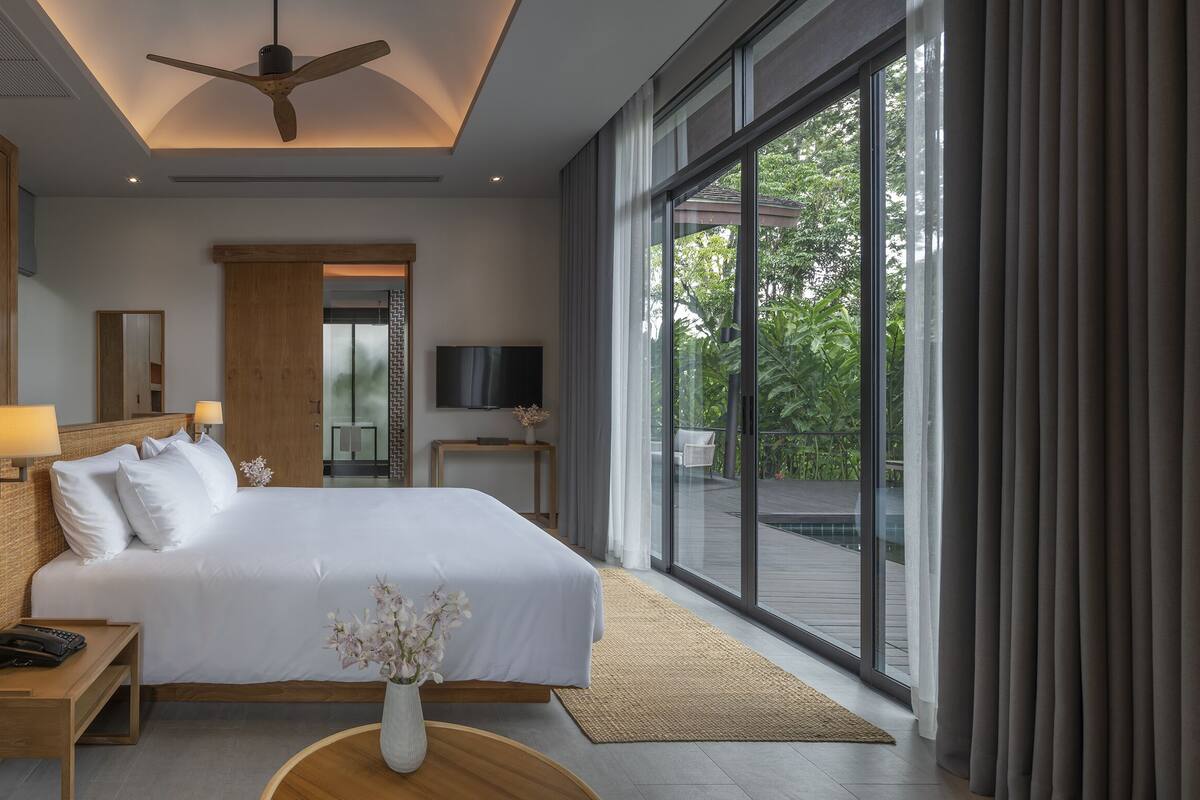 A modern hotel room with a large bed, wooden wardrobe, and a balcony with a view.