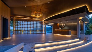 Eine moderne Lobby mit einer Rezeption, einer Wand mit Muster und einer Treppe mit integrierter Beleuchtung.