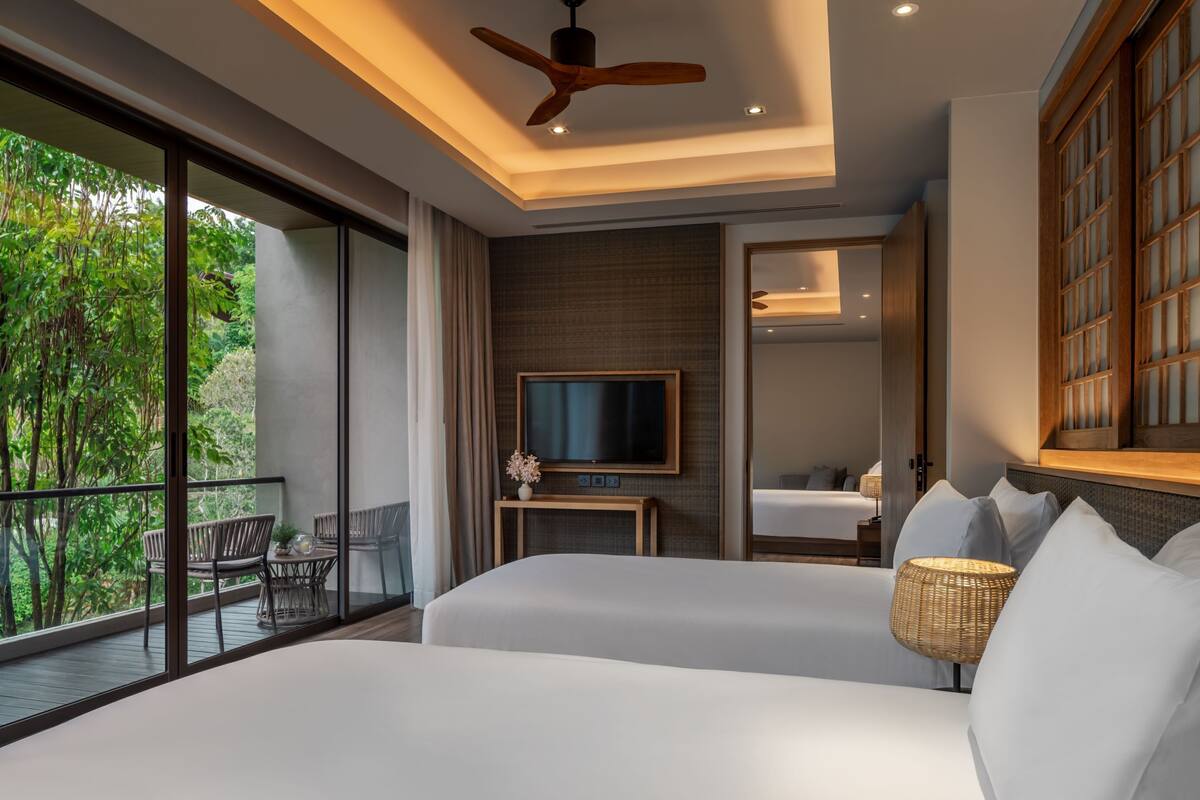 A modern hotel room with a balcony, a TV, and a bed with white bedding.