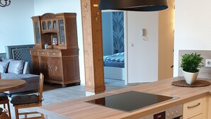 Eine moderne Küche mit einer Holztheke, Einbauofen und einer schwarzen Pendelleuchte.