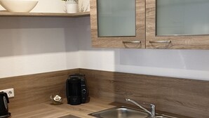 Eine moderne Küche mit weißen Schränken, einer Holz Arbeitsplatte, einer Edelstahl-Spüle und einer Kaffeemaschine.
