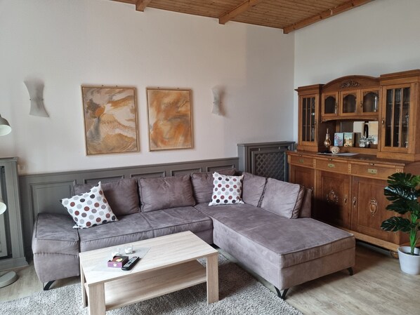 Una sala de estar con un sofá modular, un aparador de madera y arte abstracto en la pared.