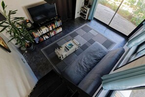 A modern living room with a sofa, a coffee table, a bookshelf, and a TV.