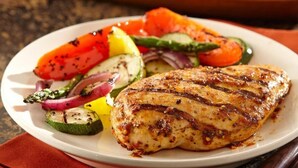 A plate with grilled chicken and a side salad. - Hotel Lindaraja (Albolote)