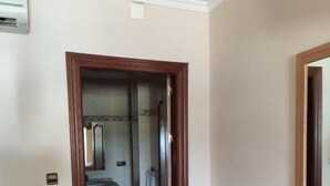 A hotel room with a wooden bench, a bathroom with a shower, and a mirror above the sink. - Hotel Lindaraja (Albolote)