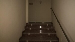 A staircase with a handrail, leading to a landing with a door marked with a 'V'. - Hotel Lindaraja (Albolote)