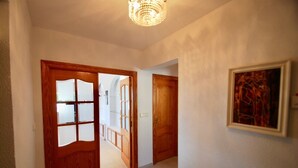 A hallway with wooden doors, a chandelier, and a framed abstract painting on the wall. - The Great Luxury Villa Villa of Atenea (Cautivador)