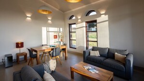 Ein geräumiges Wohnzimmer mit einem dunkelgrauen Sofa, einem Holztisch und einem Essbereich mit Holztisch und Stühlen.