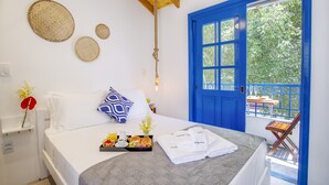 A bedroom with a bed, a breakfast tray, towels, and a view of greenery through a blue door. - Vila Grega (São Paulo)