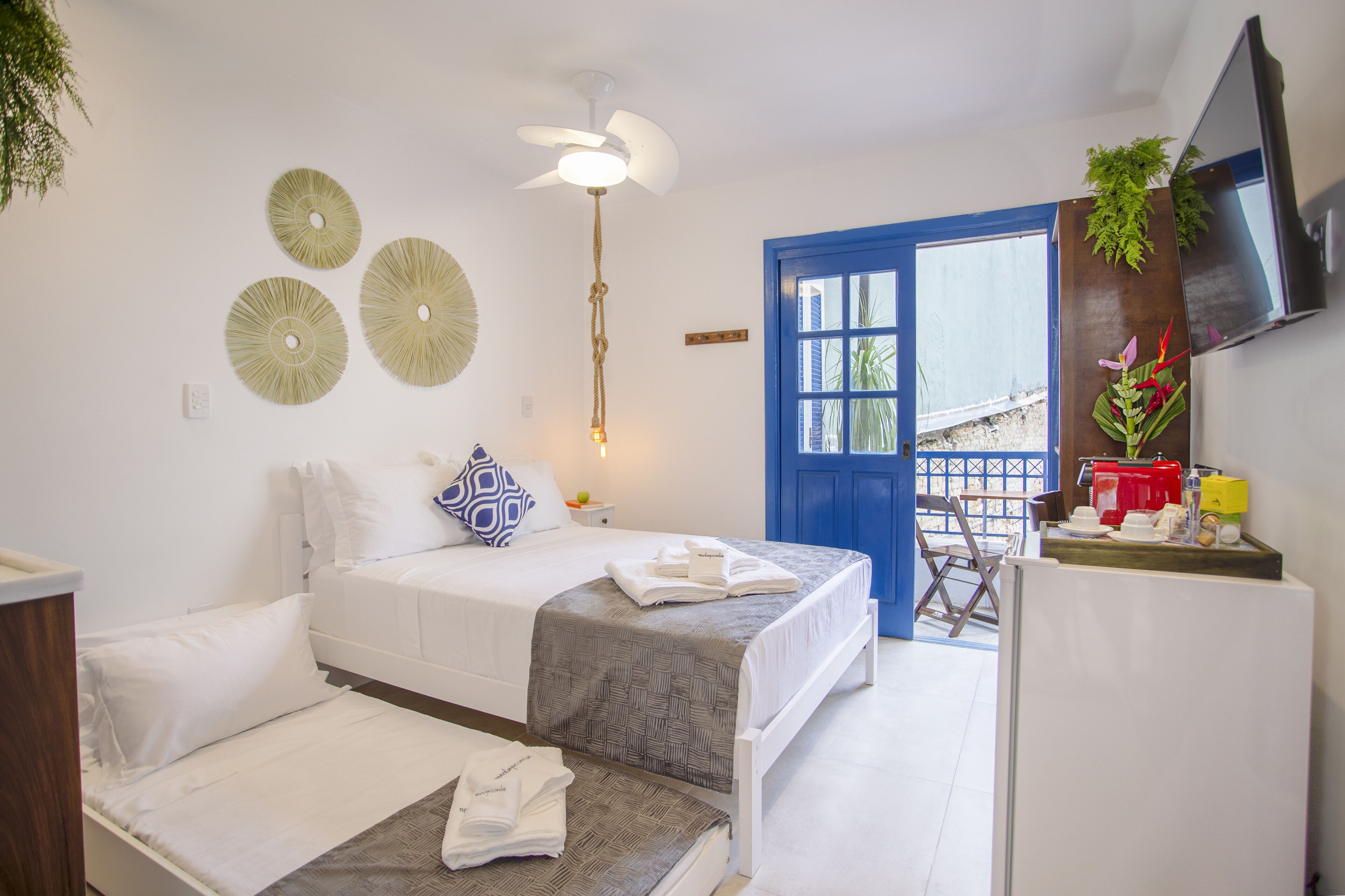 Habitación de hotel con una cama, un escritorio, un televisor y una puerta azul que da al exterior.