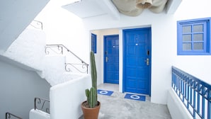 A white and blue interior with a staircase, a potted cactus, and blue doors. - Vila Grega (São Paulo)