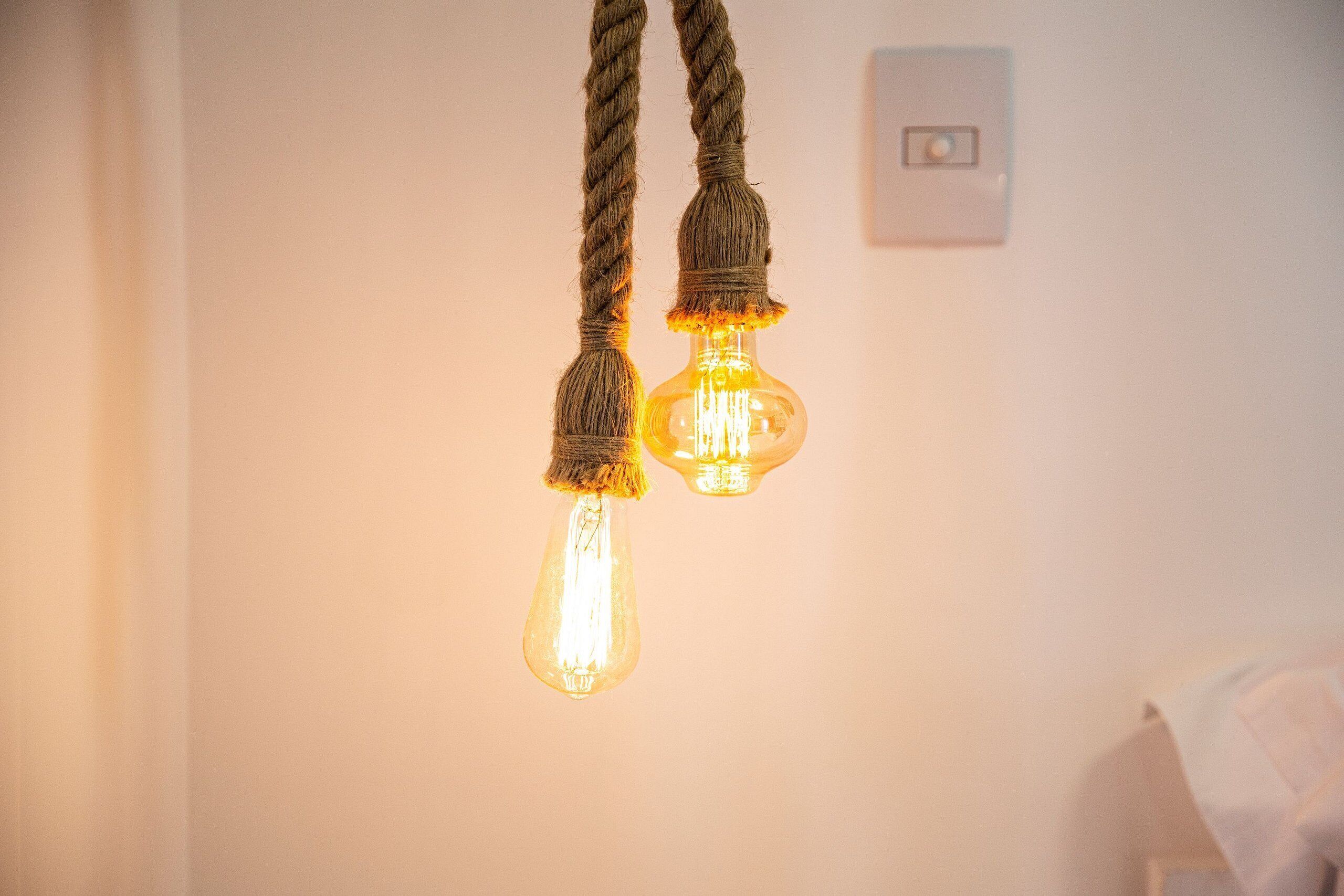 Two light bulbs with rope handles hanging from the ceiling.