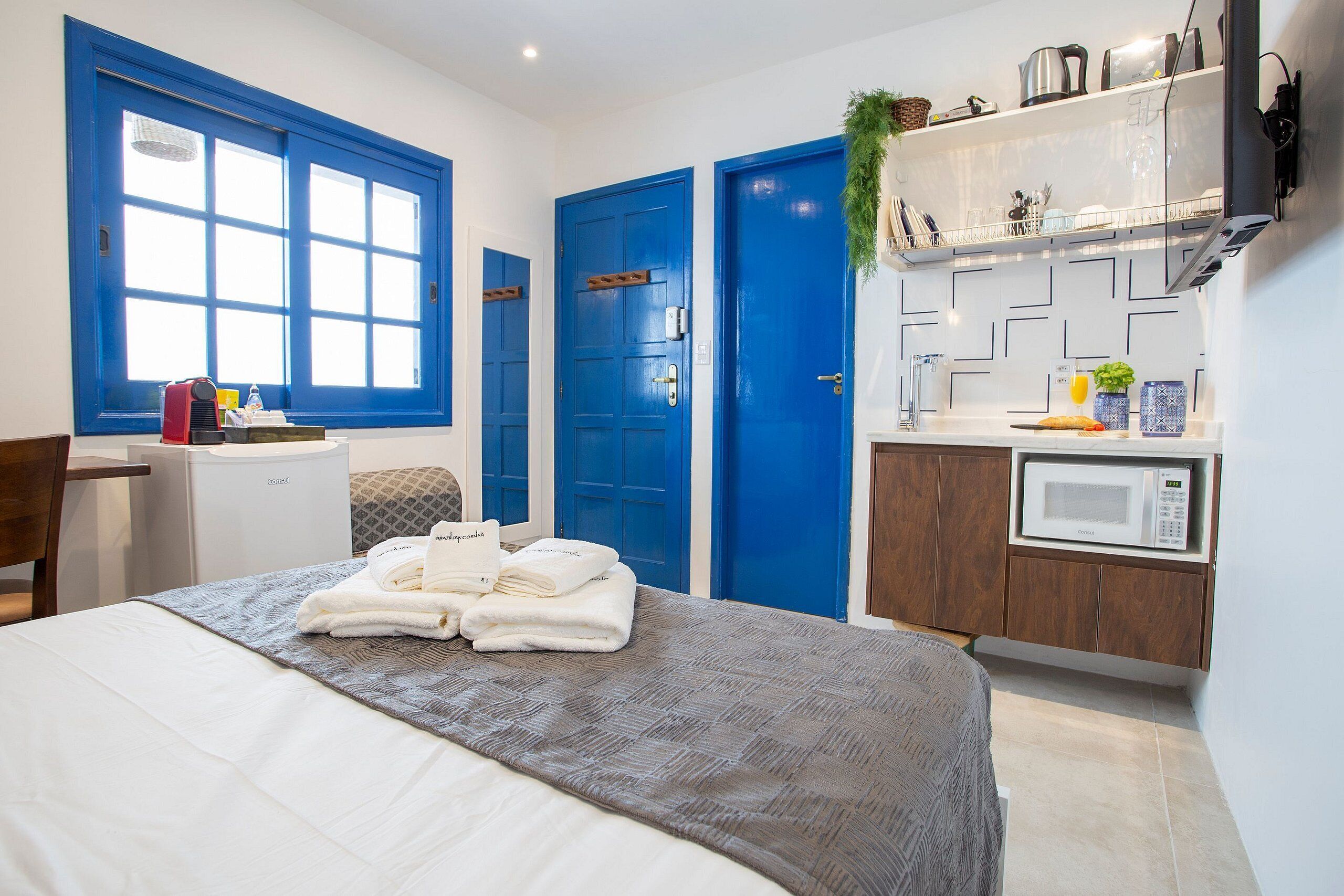 Une chambre d’hôtel équipée d’un lit, d’un bureau, d’un four à micro-ondes et d’une kitchenette.