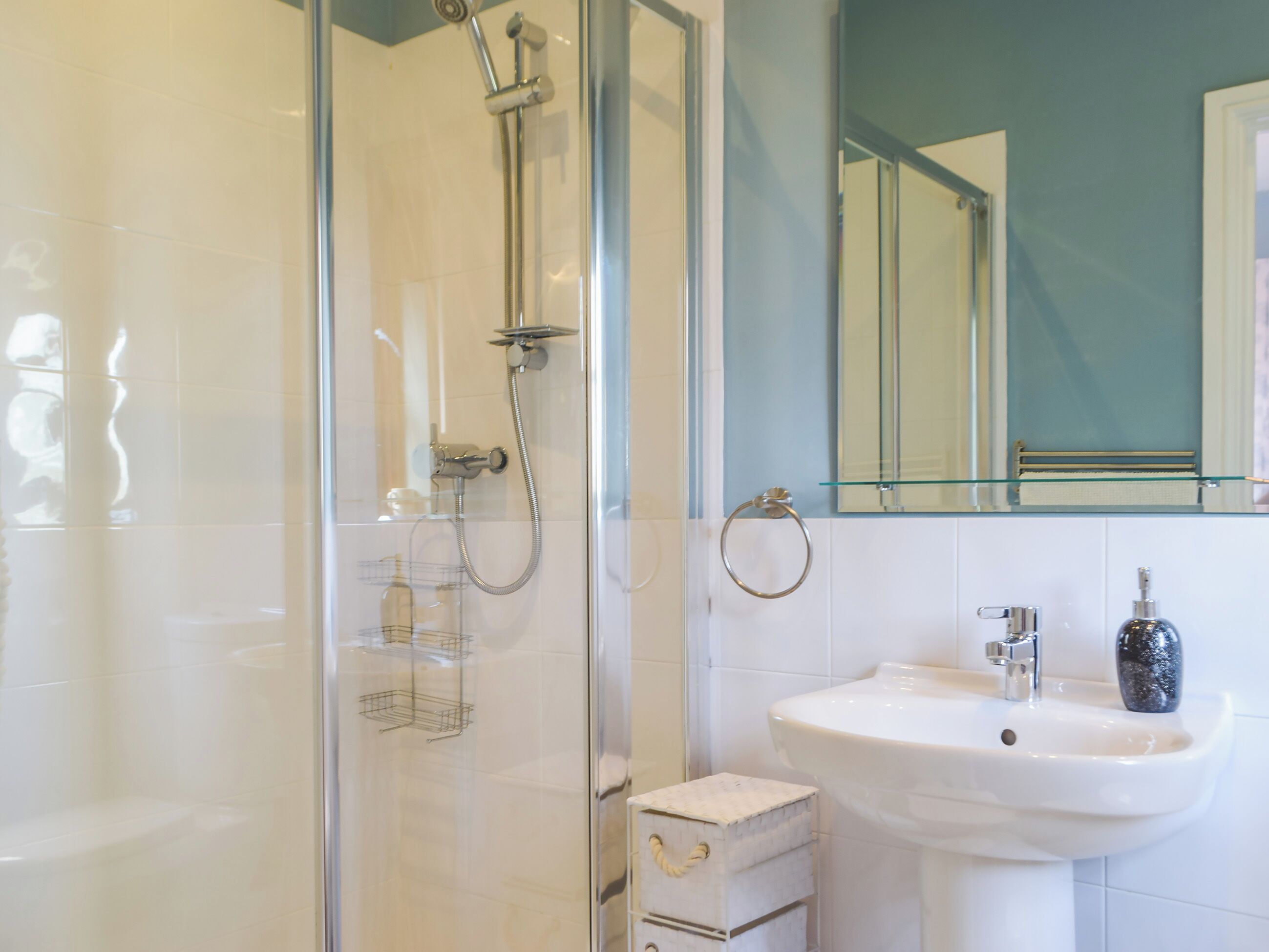 A modern bathroom with a glass-enclosed shower, a white sink, and a mirror above the sink.