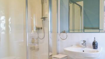 A modern bathroom with a glass-enclosed shower, a white sink, and a mirror above the sink.