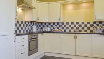 A modern kitchen with white cabinets, a stainless steel oven, a checkered backsplash, and a sink with a faucet.