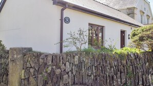 A white building with a stone wall in front, a window, and a door.
