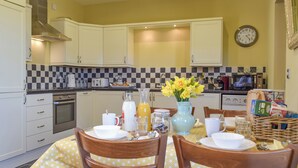 A kitchen with white cabinets, a checkered backsplash, and a dining table set with chairs.