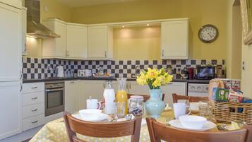 A kitchen with white cabinets, a checkered backsplash, and a dining table set with chairs.
