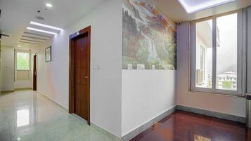 Un couloir avec une porte en bois, une fresque murale et une grande fenêtre.
