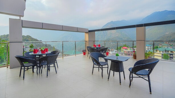 Una terraza con una mesa y sillas, con vistas a un paisaje montañoso.