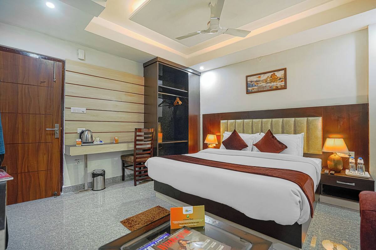A hotel room with a large bed, a desk with a chair, a wardrobe, and a ceiling fan.