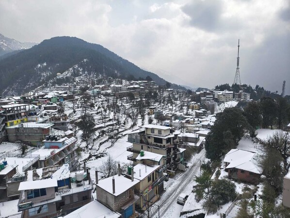 Un pueblo cubierto de nieve con edificios, una carretera y una montaña al fondo.