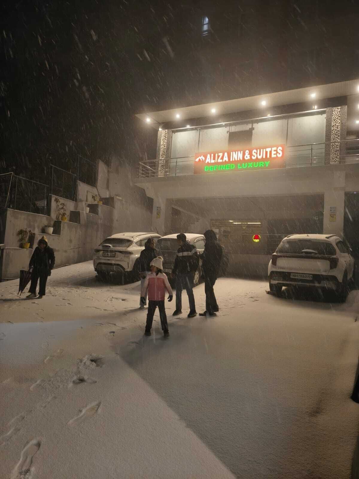 Entrada de un hotel con un letrero que dice "ALIZA INN & SUITES" y "LUJO DEFINIDO".