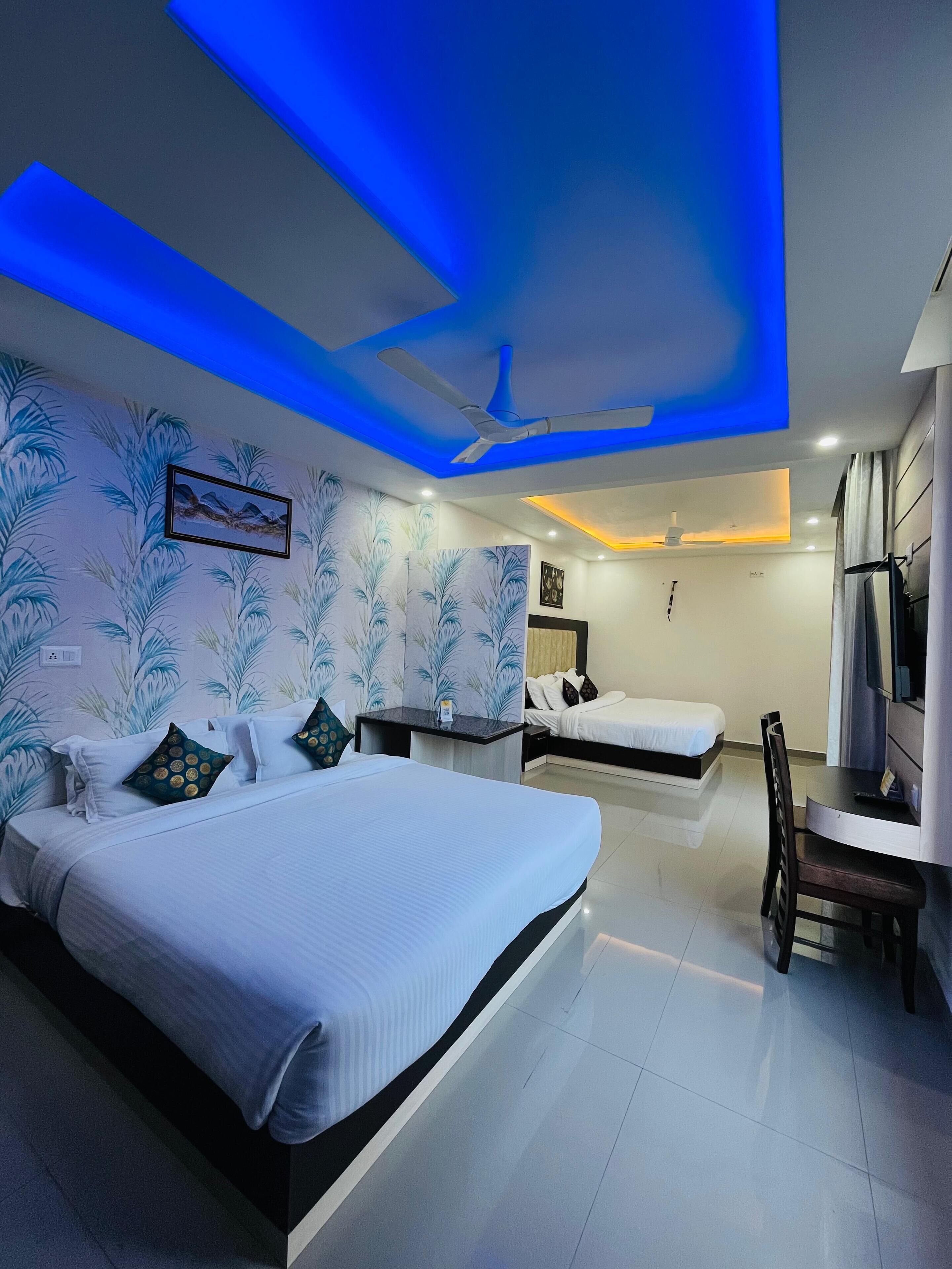 A hotel room with two beds, a desk, and a ceiling fan.