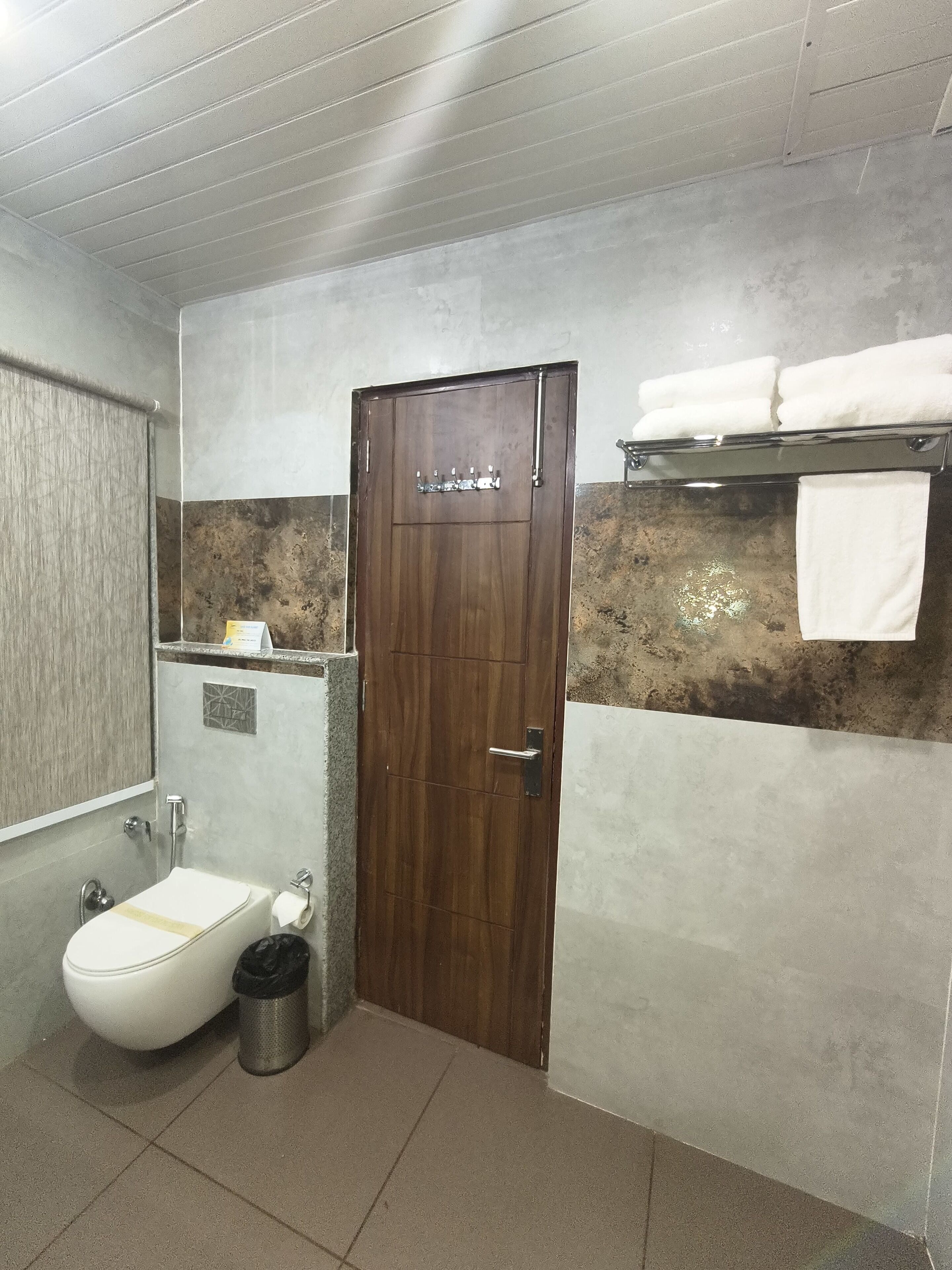 A bathroom with a wooden door, a white sink, a toilet, and a towel rack.