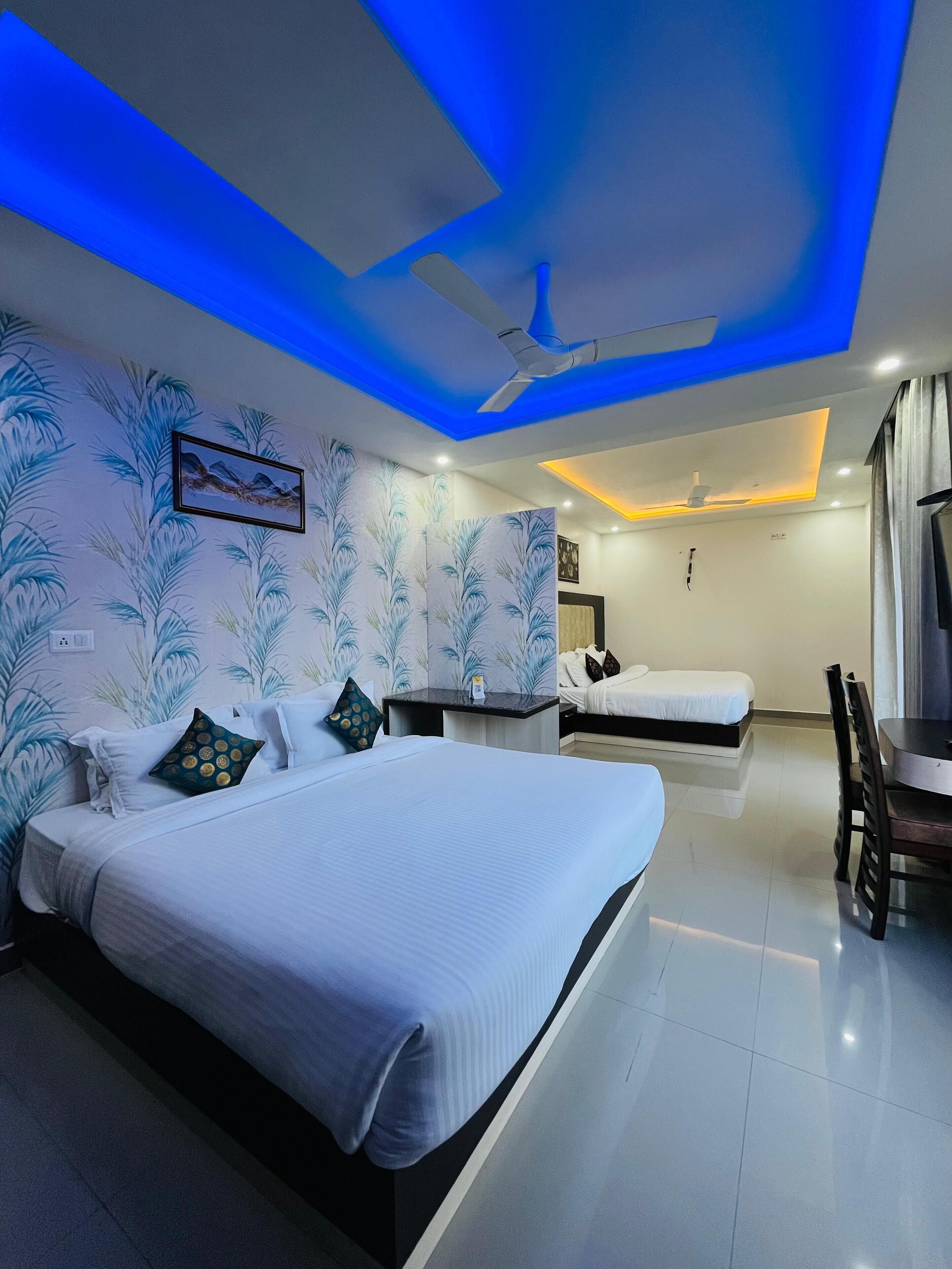 A modern hotel room with a large bed, a smaller bed, a desk, and a chair.