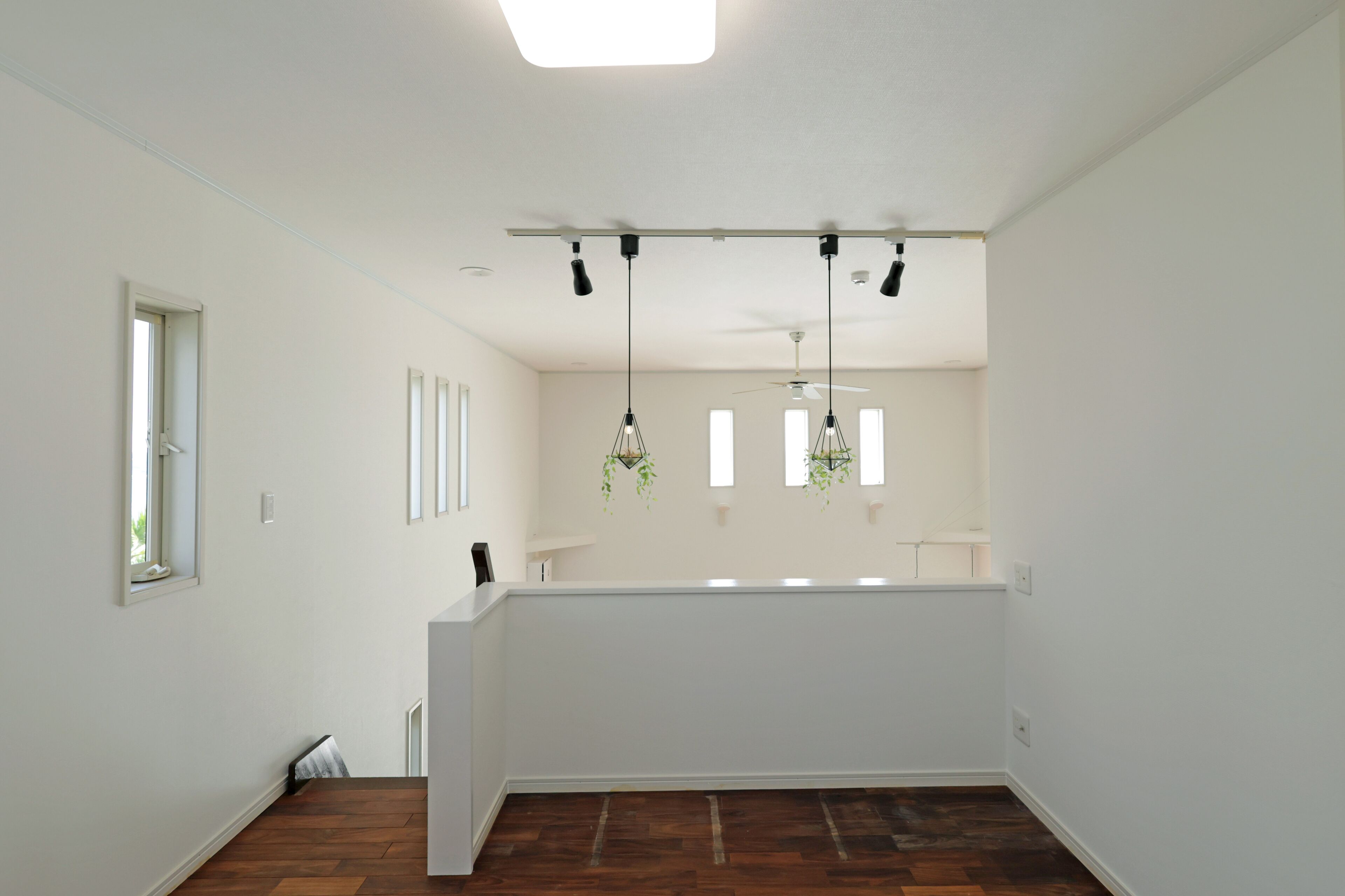 Una habitación amplia con piso de madera, paredes blancas y una lámpara de techo.