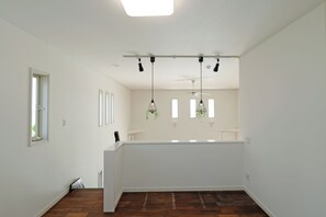 A spacious room with a wooden floor, white walls, and a ceiling light fixture. - Ocean Villa Tokunoshima (Tokunoshima)
