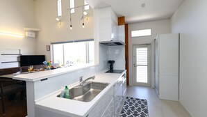 A modern kitchen with a central island, built-in appliances, and ample natural light. - Ocean Villa Tokunoshima (Tokunoshima)