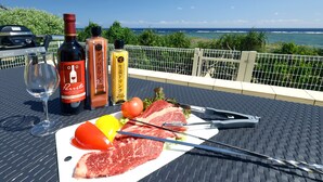 A table with a bottle of wine, a bottle of sauce, a glass of wine, a plate with meat, vegetables, and a yellow balloon. - Ocean Villa Tokunoshima (Tokunoshima)