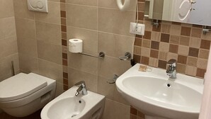 Un baño con inodoro, bidé y lavamanos.