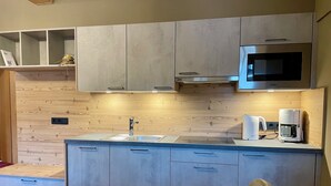 Una cucina moderna con parete in legno, mobili a incasso, lavello in acciaio inossidabile e forno a microonde.