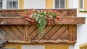 Un balcone in legno con una fioriera piena di fiori rossi e bianchi.