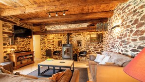 Una sala de estar acogedora con paredes de piedra, chimenea, televisor y asientos cómodos.