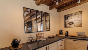 Una cocina con encimera de madera, una figurita de elefante negro, una cafetera y un adorno rústico de madera en la pared.