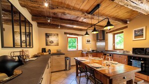 Una cocina con vigas de madera, una isla grande con taburetes de bar y electrodomésticos modernos.