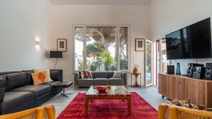 A modern living room with a black sofa, grey sofa, red rug, wooden coffee table, and a TV on the wall. - LV Premier LA2 Pool AC Garden sea View  (Sesimbra)