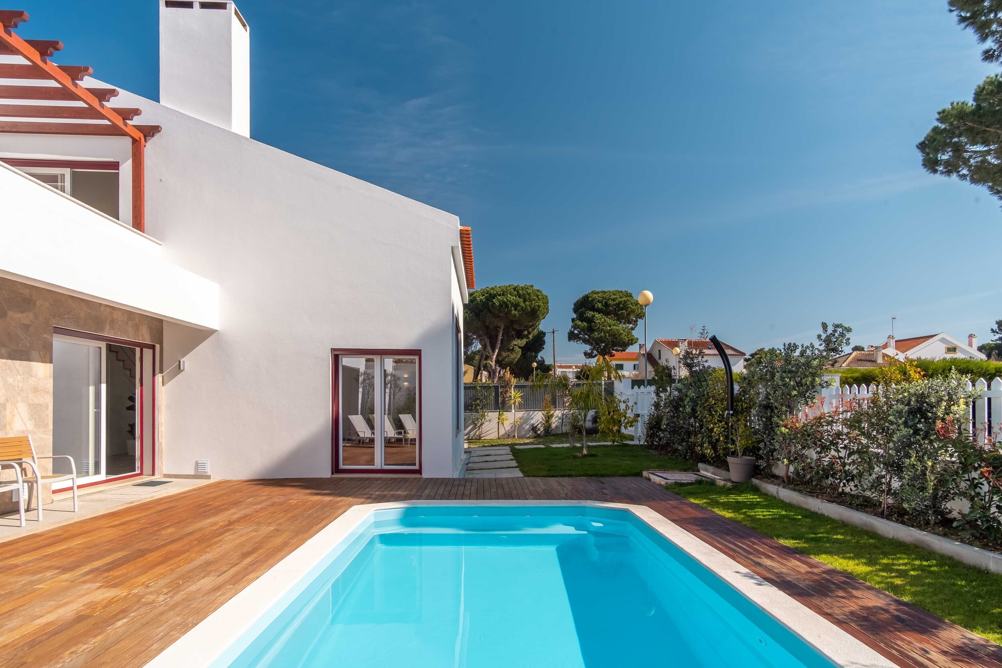 A modern house with a swimming pool, a wooden deck, and a well-maintained garden.