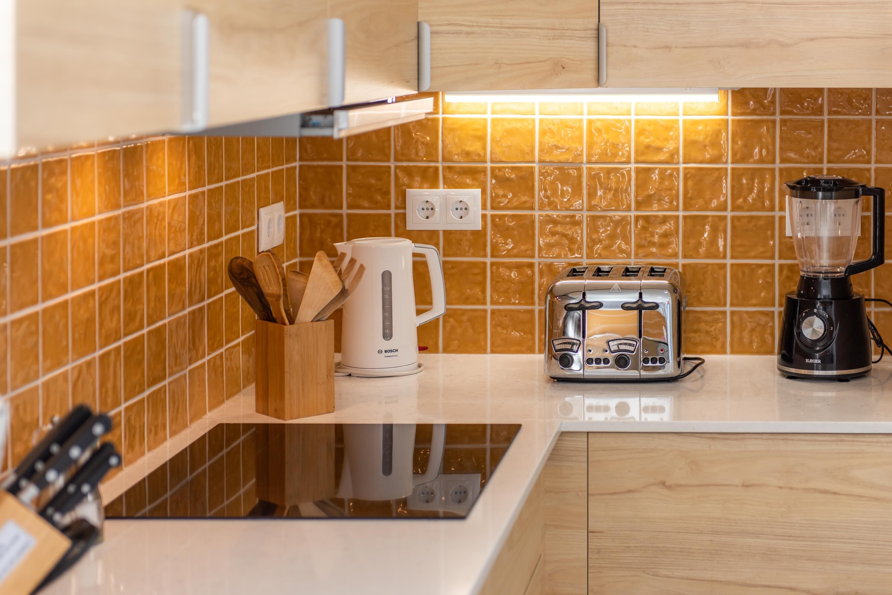 Una cocina con una cafetera Bosch, un tostador y una licuadora sobre la encimera.