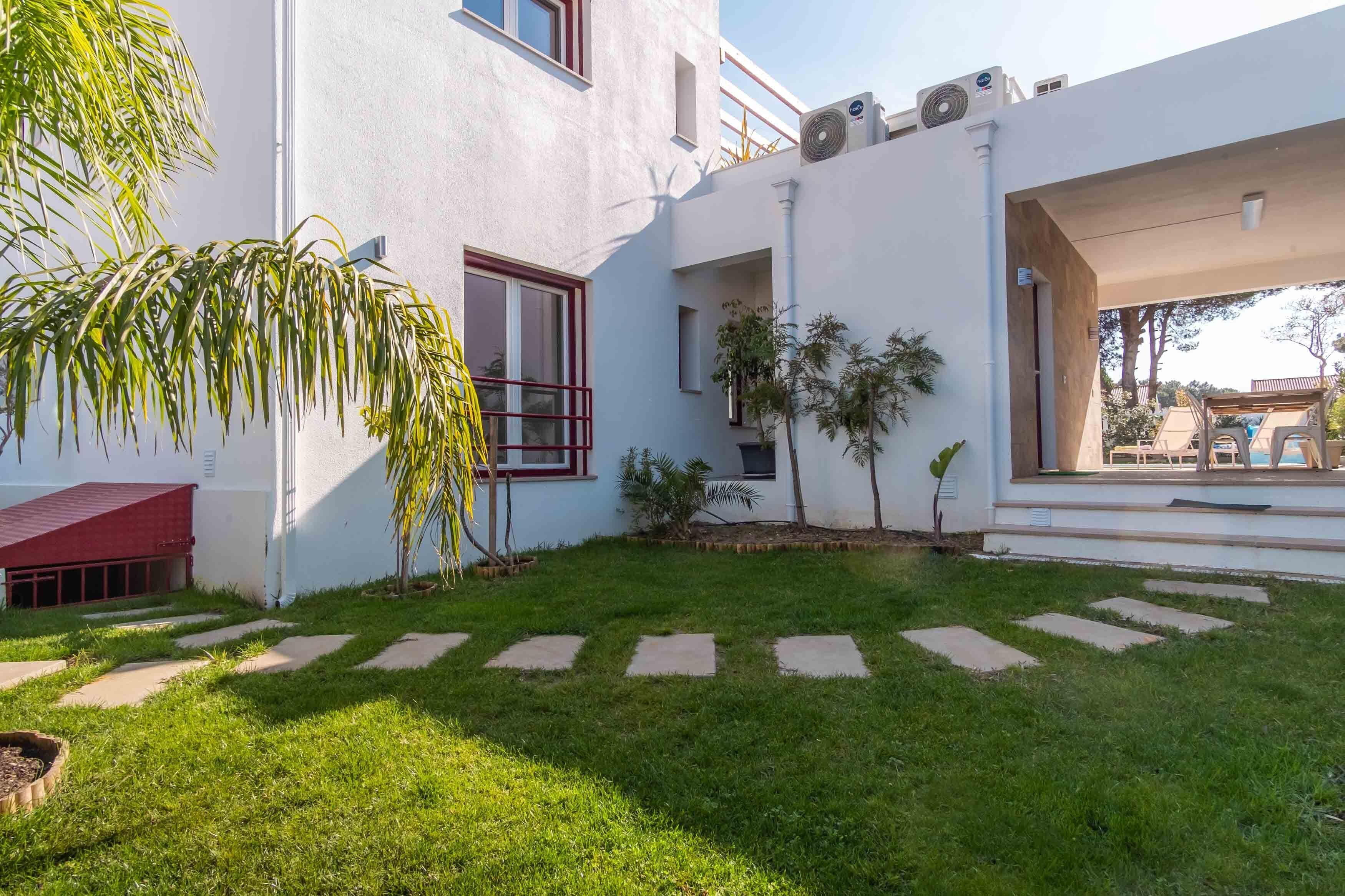 A modern building with a white exterior, a red roof, and a small garden area with stepping stones.